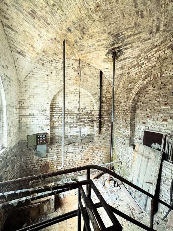 Blick von oben im Wasserturm auf gemauerte Tonnengewölbe und historische Rohrleitungen